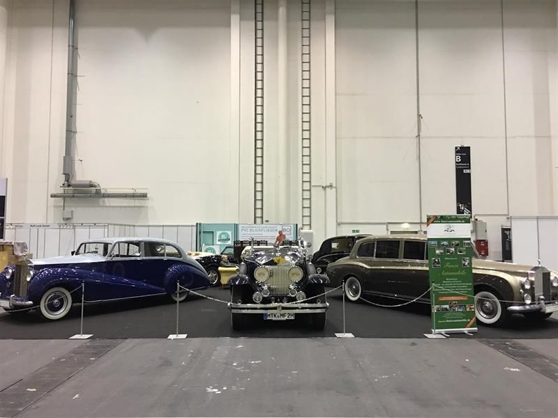 In einem großen Raum sind drei alte Autos ausgestellt.