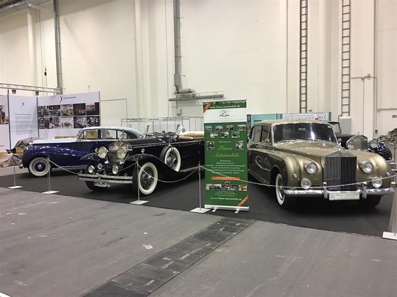 Zwei alte Autos sind nebeneinander in einem Gebäude geparkt.