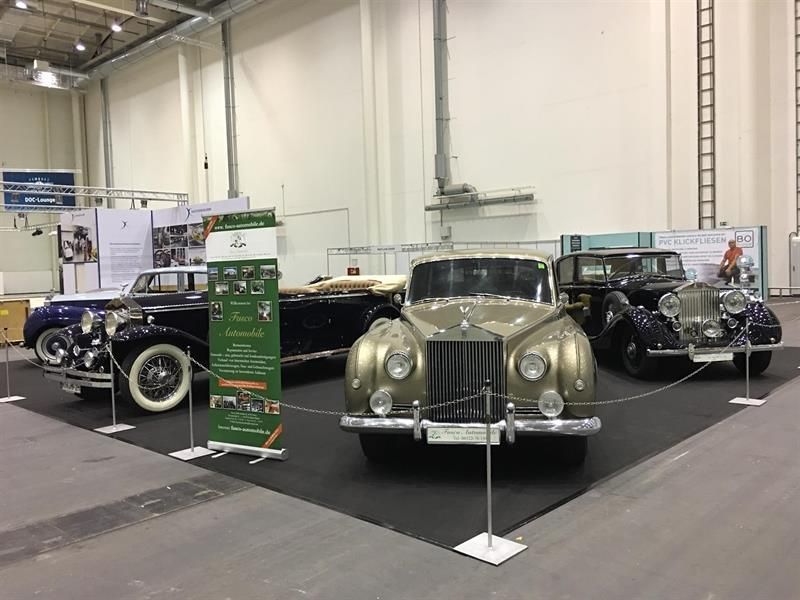 In einem Ausstellungsraum steht eine Gruppe alter Autos aufgereiht.