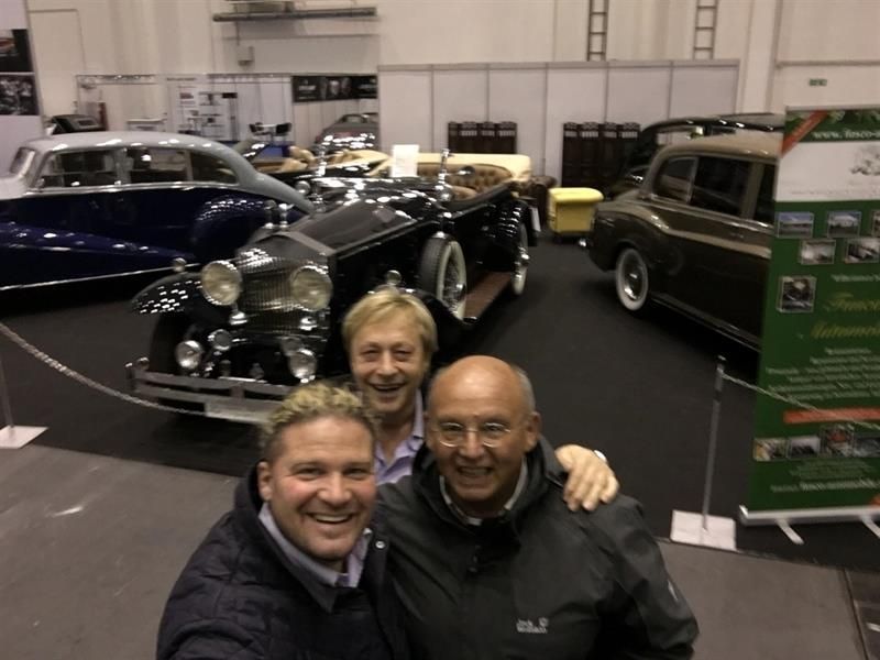 Drei Männer posieren für ein Foto vor einem alten Auto