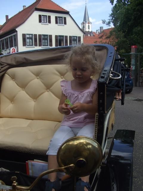 Ein kleines Mädchen sitzt auf dem Rücksitz eines alten Autos