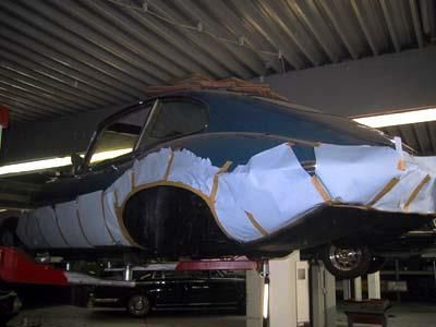 Ein blaues Auto steht auf einer Hebebühne in einer Garage.