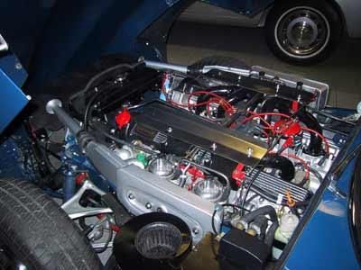 Zu sehen ist der Motor eines blauen Autos mit geöffneter Motorhaube.