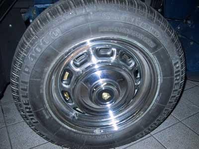 Auf einem gefliesten Boden liegt ein Reifen mit Chromfelge.