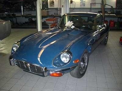 Ein blauer Jaguar E-Type steht in einer Garage.