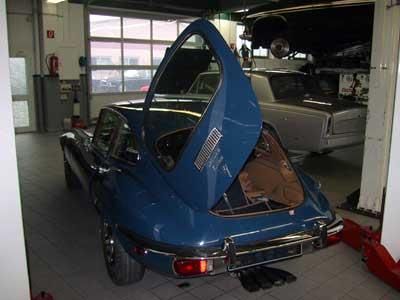 Ein blaues Auto mit geöffneter Motorhaube steht in einer Garage.