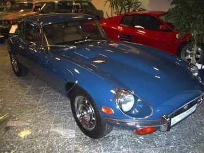 Ein blaues Auto steht in einer Garage neben einem roten Auto.