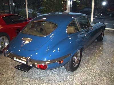 In einem Ausstellungsraum parkt ein blaues Auto neben einem roten Auto.