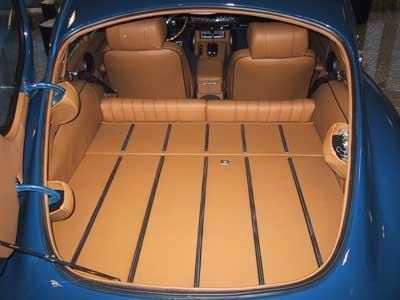 Der Kofferraum eines blauen Autos mit braunen Ledersitzen und Holzboden.