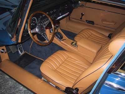 Der Innenraum eines blauen Autos mit braunen Ledersitzen und einem Holzlenkrad.