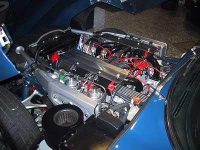 Zu sehen ist der Motor eines blauen Autos mit geöffneter Motorhaube.