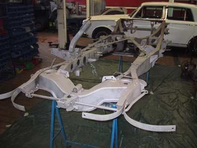 Ein Autorahmen steht auf einem Tisch in einer Garage neben einem weißen Auto.