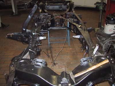 Ein Autochassis liegt auf einem Ziegelboden in einer Garage.