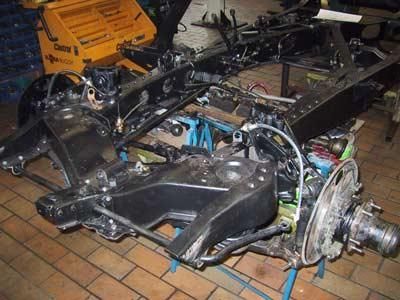 Ein Autochassis liegt auf einem Ziegelboden in einer Garage.