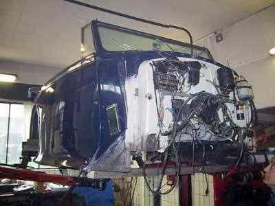 Ein blau-weißes Auto steht auf einer Hebebühne in einer Garage.