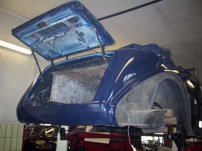 Ein blaues Auto mit geöffneter Motorhaube steht auf einer Hebebühne in einer Garage.