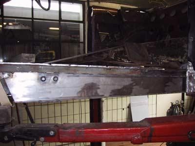 Auf einem roten Kran in einer Garage liegt ein Stück Metall.