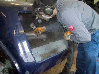 Ein Mann arbeitet in einer Garage an einem blauen Auto.