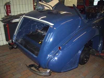 Ein blaues Auto mit geöffnetem Kofferraum steht in einer Garage.