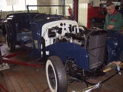 Ein Mann arbeitet in einer Garage an einem alten Auto.