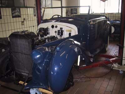 Ein blau-weißes Auto steht auf einer Hebebühne in einer Garage.