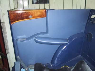 In einer Garage steht eine blaue Autotür mit Holzverkleidung.