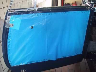 Eine blaue Plane bedeckt eine Autotür in einer Garage.