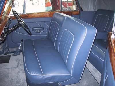 Der Innenraum eines Autos mit blauen Ledersitzen und einem Holzlenkrad.