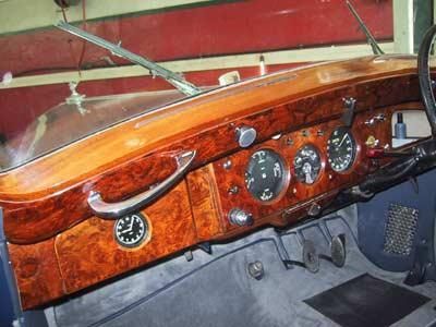 Das Armaturenbrett eines alten Autos ist aus Holz und hat eine Uhr darauf.