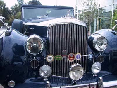 Zwei alte Autos stehen nebeneinander vor einem Gebäude.