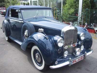 Ein blaues Auto mit weißen Reifen und einem Nummernschild mit der Aufschrift „rr“