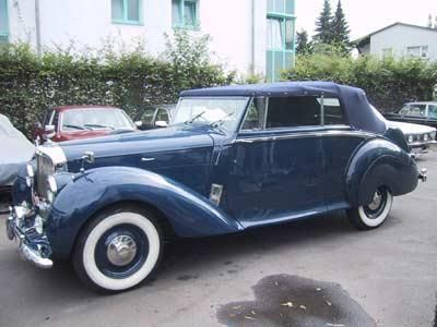 Ein blaues Auto mit weißen Reifen steht auf einem Parkplatz