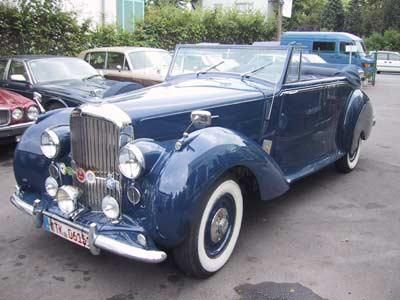 Ein blaues Auto mit weißen Reifen steht auf einem Parkplatz