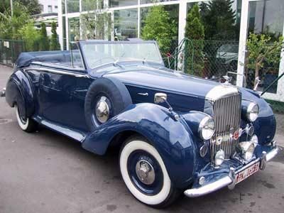 Ein blaues Auto mit weißen Reifen steht vor einem Gebäude.