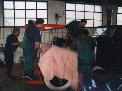 Eine Gruppe von Männern arbeitet in einer Garage an einem Auto