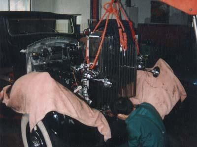 Ein schwarzes Auto wird von einem Kran in eine Garage gehoben