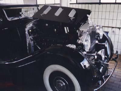 Ein schwarzes Auto mit geöffneter Motorhaube steht in einer Garage.