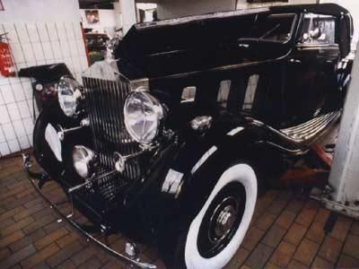 Ein schwarzes Auto mit weißen Reifen steht in einer Garage.