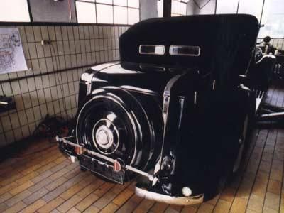 Ein schwarzes Auto mit geöffneter Motorhaube steht in einer Garage