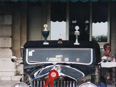 Ein schwarzes Auto mit einer roten Schleife an der Vorderseite steht vor einem Gebäude.