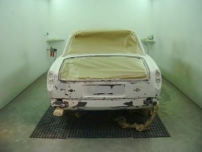 Ein weißes Auto wird in einer Lackierkabine lackiert.