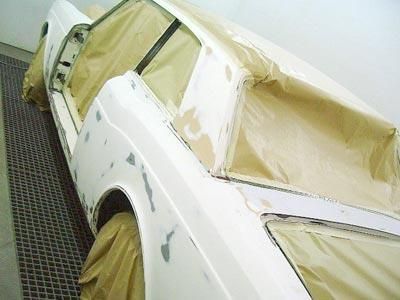 Ein weißes Auto wird in einer Lackierkabine lackiert