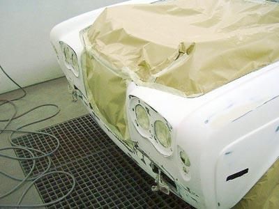 Ein weißes Auto wird in einer Lackierkabine lackiert.