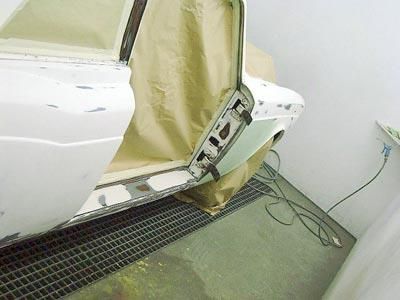 Ein weißes Auto wird in einer Lackierkabine lackiert.