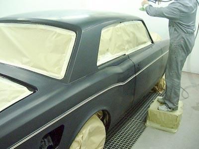 Ein Mann lackiert ein schwarzes Auto in einer Garage