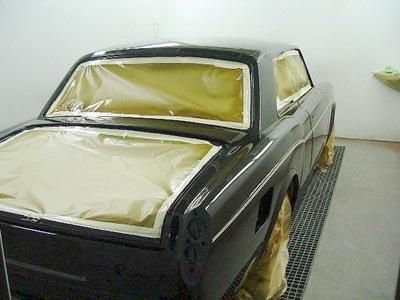 In einer Garage wird ein schwarzes Auto lackiert.