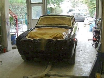 Ein schwarzes Auto steht auf einer Hebebühne in einer Garage