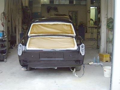 In einer Garage wird ein schwarzes Auto lackiert.