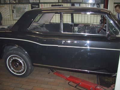 Ein schwarzes Auto steht auf einer Hebebühne in einer Garage