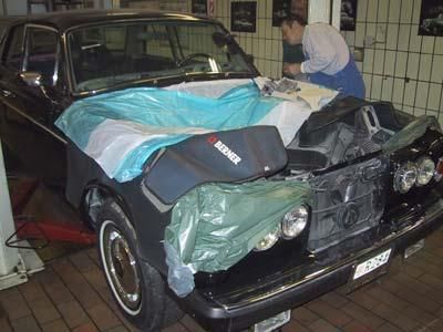 Ein Mann arbeitet in einer Garage an einem schwarzen Auto